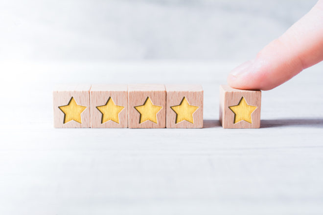 5 Star Ranking Formed By Wooden Blocks And Arranged By A Male Finger On White Table