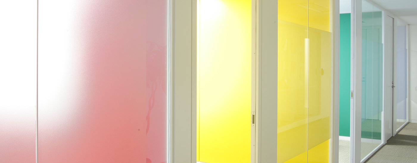 廊下とガラスで仕切られた会議室。赤、黄、緑など発色の良い壁が印象的。