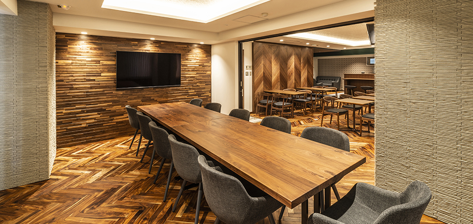 壁材や木目調の大きなテーブル、丸みのあるグレーの椅子などデザインにこだわった自然の温もり溢れる会議室